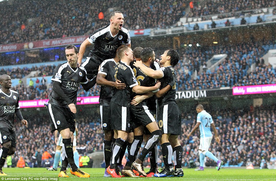 Huth is mobbed by his Leicester team-mates as the players celebrate the goal in the third minute as the rain comes down at the Etihad